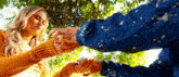 a man and a woman are holding hands in a park . the woman is wearing a yellow sweater .