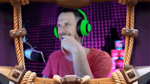 a man wearing green headphones is sitting in front of a microphone in a frame .