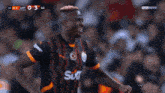 a soccer player in a black and orange jersey celebrates a goal