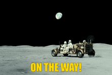 two astronauts are driving a vehicle on the moon with the words on the way in yellow letters