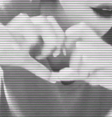 a black and white photo of a woman making a heart shape with her hands .