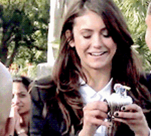 a woman is smiling while holding a cupcake in her hands