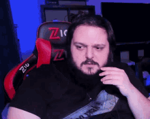 a man with a beard is sitting in a gaming chair with the letter z on it .