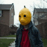 a man wearing a yellow lemon mask with a sad face