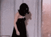 a woman in a black dress and pearl necklace is dancing .