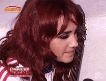 a woman with red hair is holding a guitar in front of a screen that says povestiri noapte