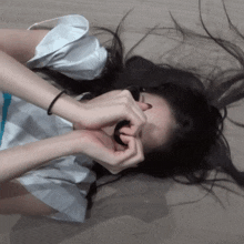 a woman laying on the floor covering her face with her hair