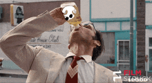 a man in a suit and tie drinks from a bottle with a dog on it
