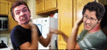 two men are fighting in a kitchen with their faces on their arms .