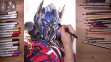a person is drawing a picture of optimus prime surrounded by colored pencils and markers