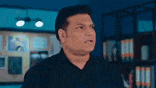 a man in a black shirt is standing in a dark room .