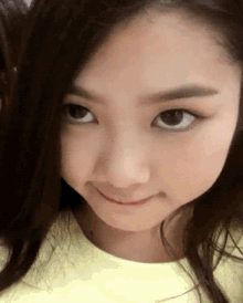 a close up of a girl 's face with a yellow shirt