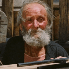 a man with a beard is holding a gun and looking at the camera