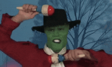 a man with a green mask on his face is holding a maraca