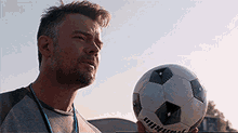a man is holding a soccer ball in his hand and looking up at the sky .