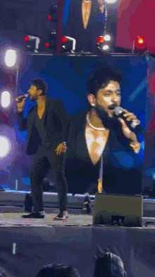 a man in a suit singing into a microphone on stage