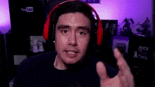 a man wearing red headphones is giving a thumbs up sign .