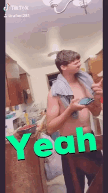 a shirtless man with a towel around his neck is standing in a kitchen with yeah written in green
