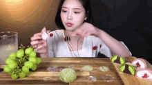 a woman is sitting at a table with a bunch of grapes and a glass of water