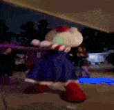 a hello kitty doll is dancing on a sidewalk at night