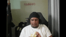 a man wearing a beanie is eating a banana .