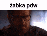 a man with glasses and a beard is looking at the camera with the words zabka pdw written above him .