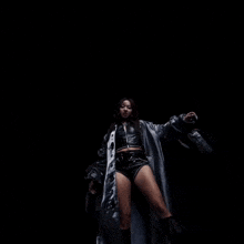 a woman in a black trench coat is looking down at the camera