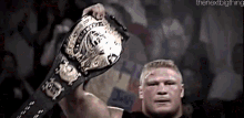 a wrestler is holding a world heavyweight championship belt in his hands .