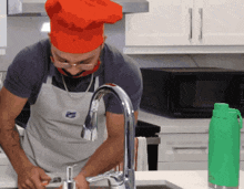 a man wearing a chef 's hat and apron is washing dishes in a kitchen
