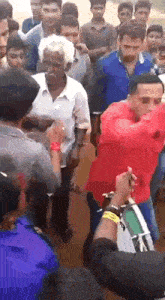 a man in a red shirt is playing a drum in a crowd
