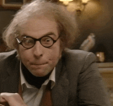 a close up of a man wearing glasses and a suit making a funny face .