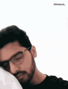 a man with glasses and a beard is sleeping on a bed