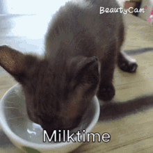 a kitten drinking milk from a white bowl with the words milktime below it