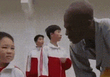 a man is talking to a group of children in a gym .