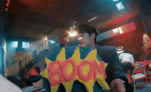 a man holding a cake that says boom on it