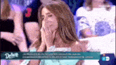 a woman is covering her face with her hands while sitting in front of a crowd .