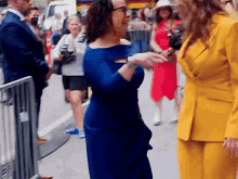 a woman in a blue dress is talking to a woman in a yellow suit .