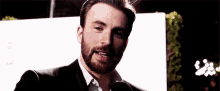 a man with a beard is standing in front of a microphone .