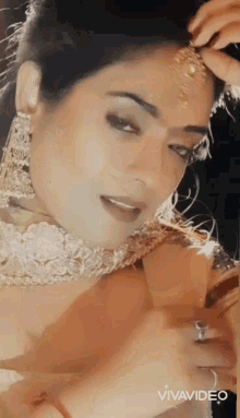 a woman wearing a necklace and earrings looks at herself in a vivavideo photo