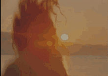 a woman is running on a beach at sunset with her hair blowing in the wind .