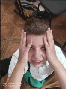 a young boy is making a funny face with his hands on his forehead