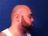 a bald man with a beard is wearing a white tank top .