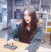 a young woman is sitting at a table using a tablet computer .