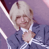 a young man with blonde hair is wearing a blue jacket with a boys planet logo on it .