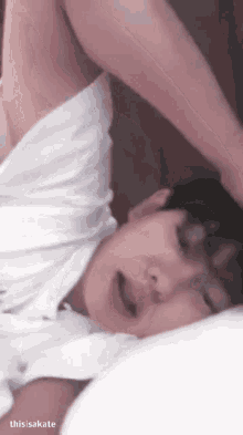 a man is laying on a bed with his arms outstretched and his mouth open .