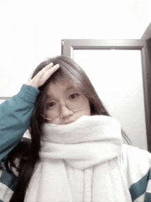 a girl wearing glasses and a scarf is taking a picture of herself