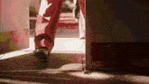 a person in red pants and black shoes is walking through a door