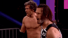 two wrestlers are standing next to each other in a ring in a dark room .