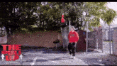 a man in a red sweatshirt is dancing in a parking lot with the words the up written on the bottom