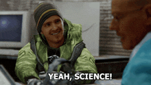 a man in a green jacket says " yeah science " in front of another man